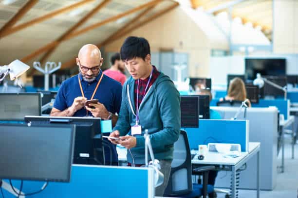 Deux employés qui regardent leur portable dans des bureaux