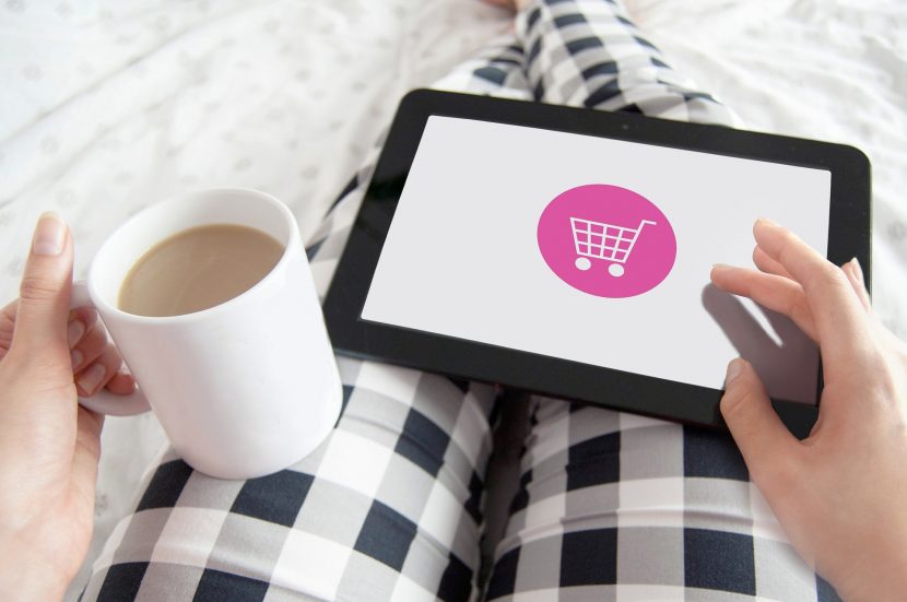 Femme qui passe une commande en ligne depuis sa tablette et qui tient une tasse dans l'autre main