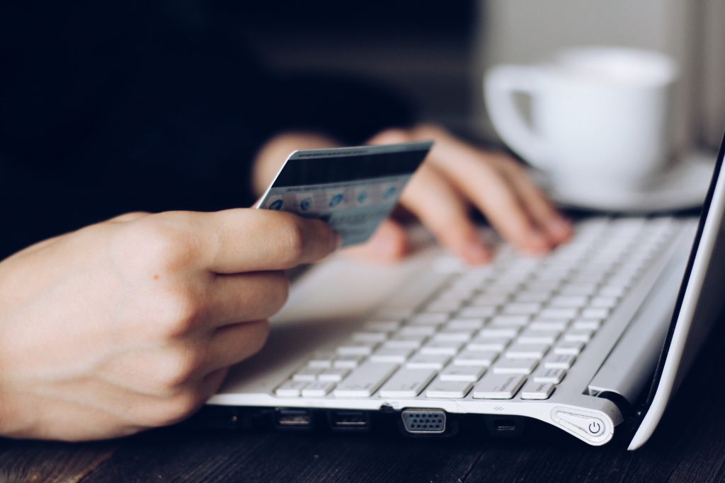 zoom sur les mains d'une personne tenant une carte bancaire près d'un clavier d'ordinateur